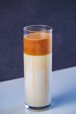 A glass of vegan milk with a layer of beaten coffee