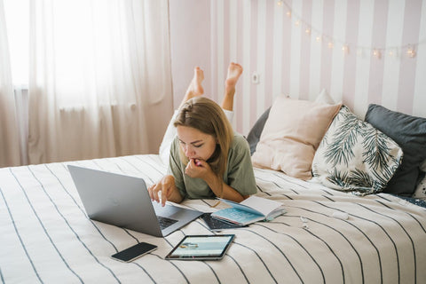 A woman lying on a bed with various gadgets around her 