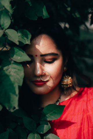 Woman in ethnic attire standing behind green leaves