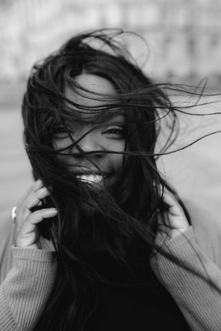 A smiling woman with her hair all over her face 