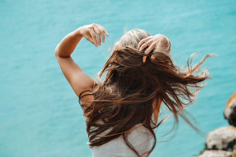 A woman feeling her hair against a blue background