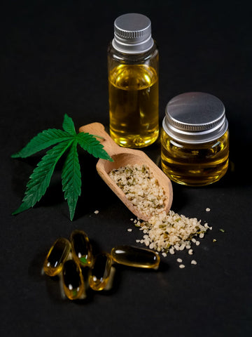 A ladle full of hempseeds with a help leaf surrounded by two hempseed oil bottles 