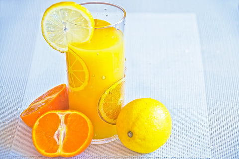 A glass of orange juice with slices of orange near the glass