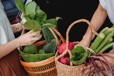 Two woman holding baskets with variety of vegetables 