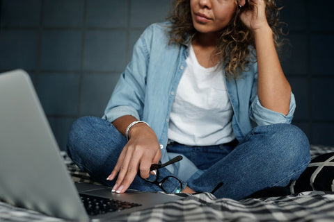 Woman wearing a t shirt and jeans sitting in front of a laptop