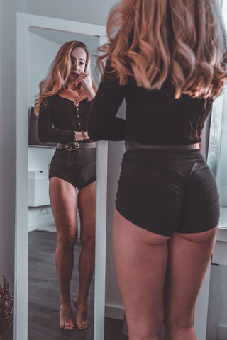 A woman with spectacle and long hair standing in front of the mirror 