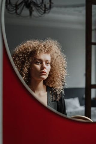 Woman with curly hair looking at herself in the mirror