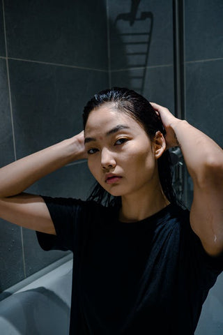 Woman wearing a black t-shirt touching her wet hair 