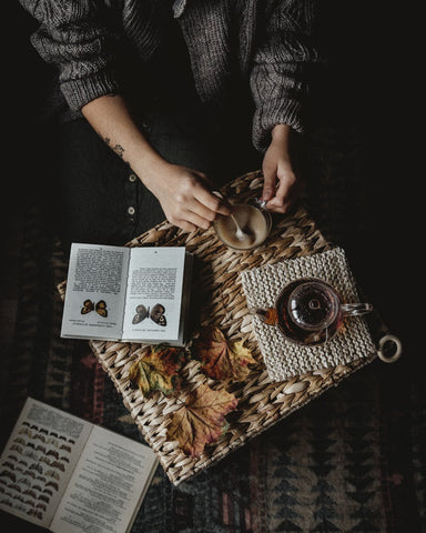 Woman making tea with books beside her 