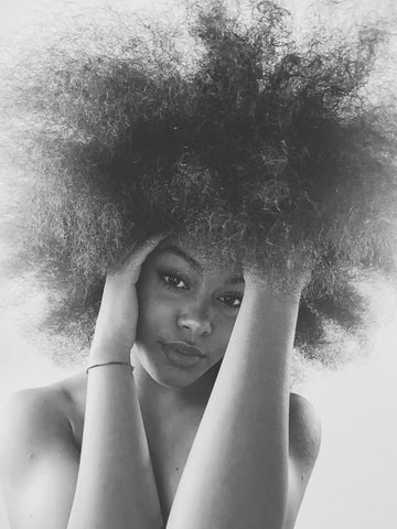 A woman touching her high volume curly hair 