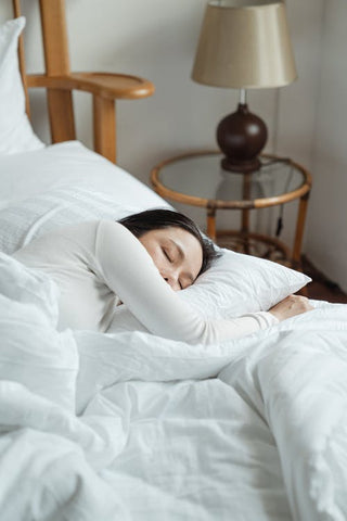 A woman deeply sleeping on a mattress under a duvet cover 