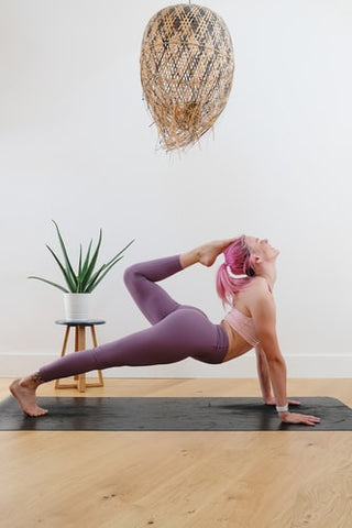 A woman holding a yoga posture on a purple yoga mat 
