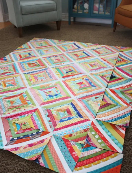 string quilt blocks of different color arranged in quilt layout on floor