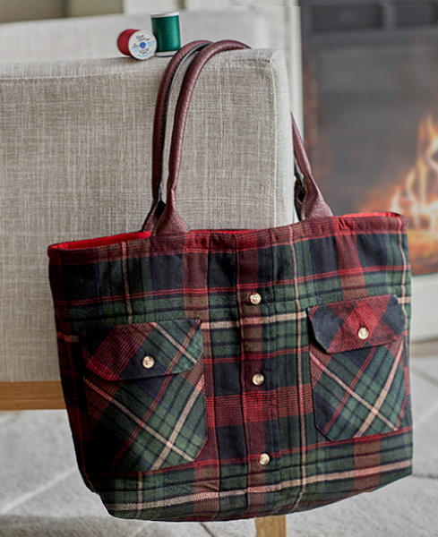 an upcycled flannel shirt with breast pockets turned into a tote hanging on a chair