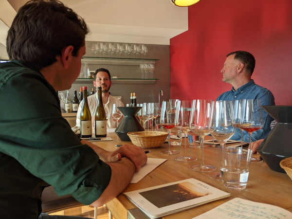 Picture of tasting room with people around the table tasting while Alex Zahel is talking through the wines