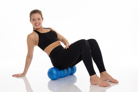 woman sitting on the rollga foam roller. rolling out her glutes