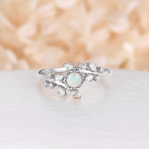 Silver engagement ring with a nature-inspired design featuring a white opal nestled amongst delicate branches adorned with diamonds