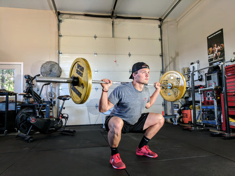 MAN SQUATTING WITH BARBELL