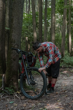 Mann schraubt an seinem Fahrrad im Wald