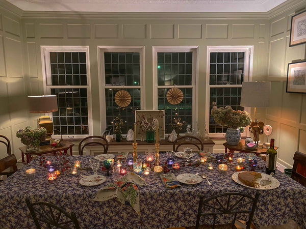 Nach dem Abendessen stimmungsvolle Aufnahme des Esszimmers mit brennenden Kerzen und leeren Tellern. Der Tisch ist mit einer blauen Tischdecke aus Bio-Leinen und bunten Servietten aus Bio-Leinen gedeckt.