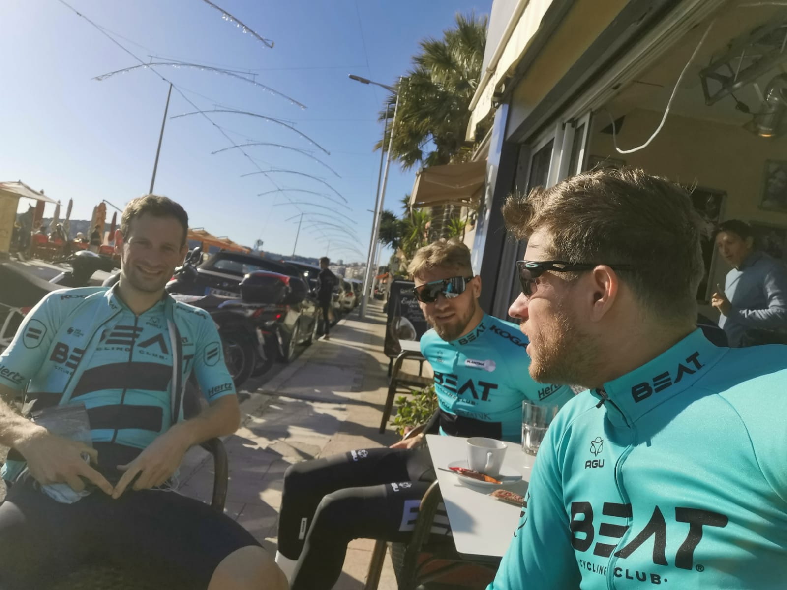 Theo Bos, Luuc Bugter en Bas van der Kooij van BEAT Cycling Club drinken koffie in de zon.