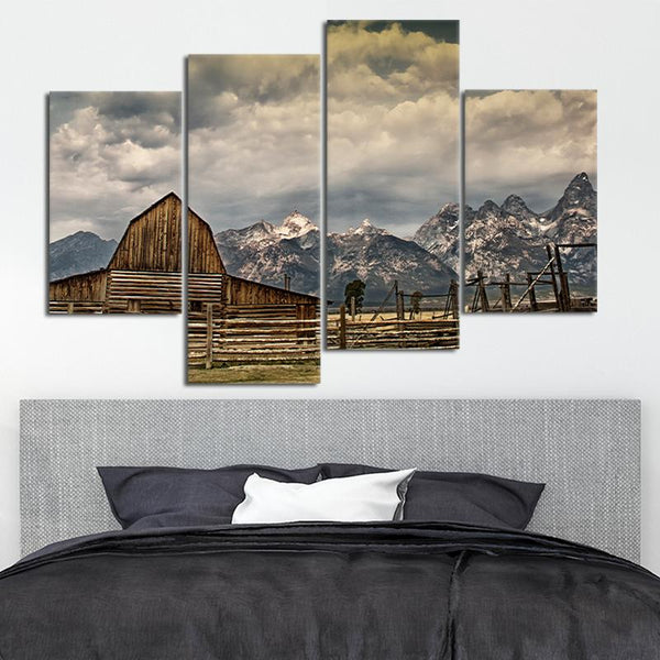 A canvas of an old barn with mountains and dark clouds in the background. 