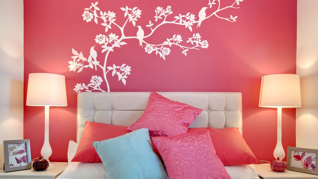 A pink wall with a mural painted on it. The mural has flowers and birds. 