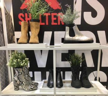 A shelf displaying shoes and boots containing plants.