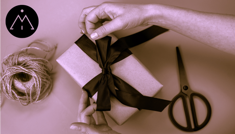 Image with woman wrapping a gift with kraft paper and black ribbon