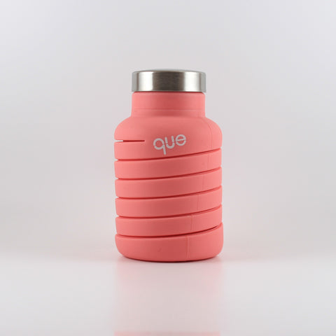 This is a photo of the que bottle - a coral pink silicone bottle with a metal cap and a spiral design