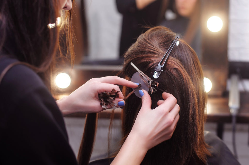 Stylist inserting hair extensions