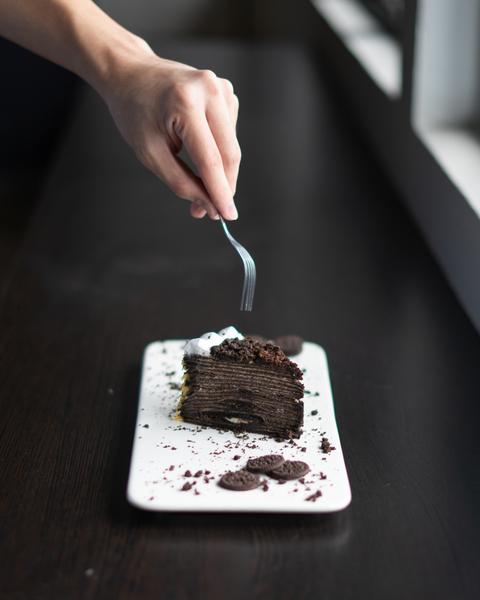 hand holding a fork to grab a piece from a chocolate cake