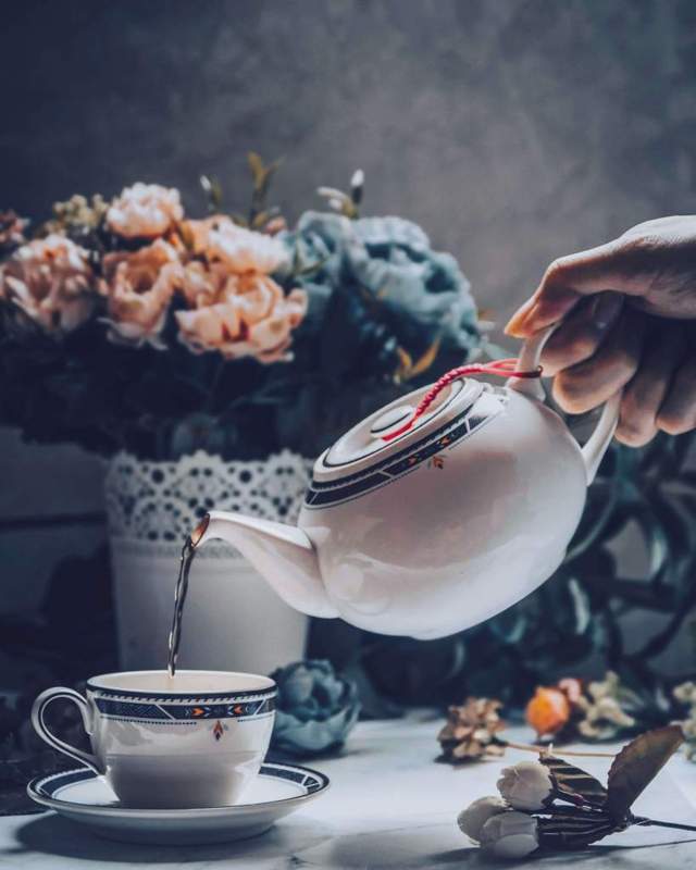 hand pouring tea from tea pot to tea cup