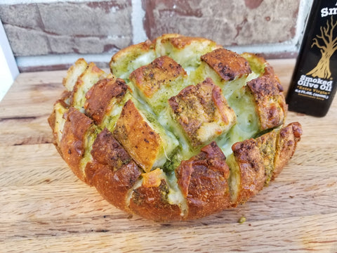 A loaf of Italian bread with pesto and mozzarella cheese.