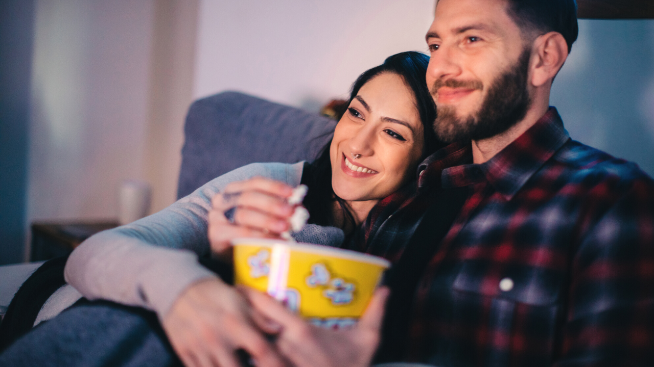 Couple enjoys popcorn at home while watching a movie