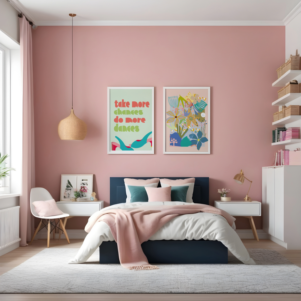 a light pink coloured bedroom with a rattan hanging lamp a denim blue base bed with mixing coloured throw pillows on the bed and two framed wall prints hanging on the wall One wall print is a text print Saying Choose more Dance more and the other wall print is a selection of abstract flowers