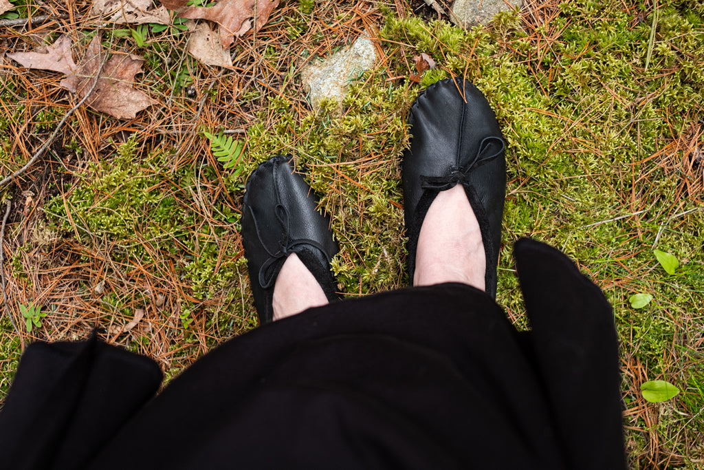 Black ballet moccasins looking down on mossy surface forest barefoot earthing