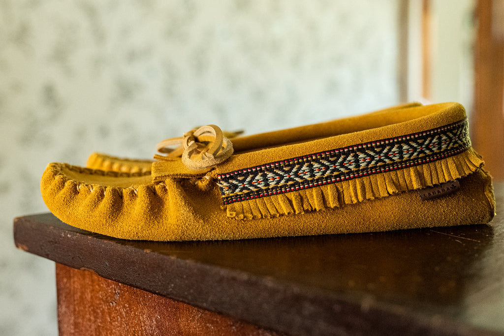 Native American accents on a pair of moccasins Indian braid style strip around fringed slippers