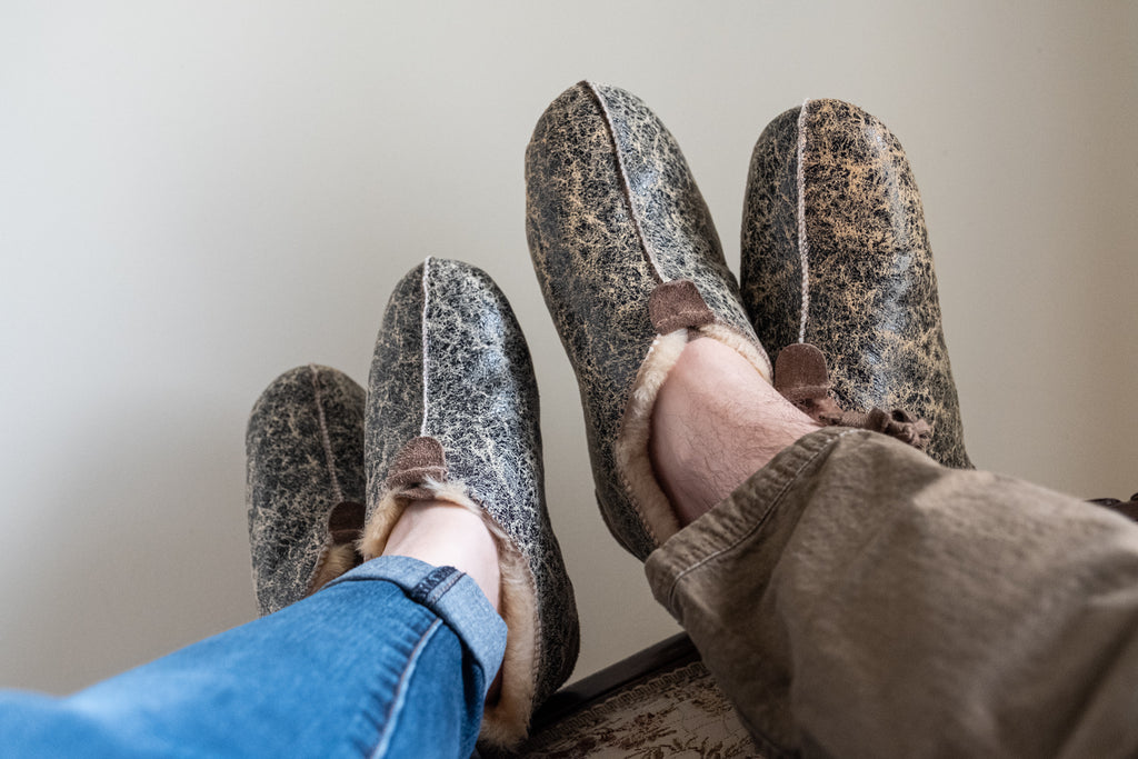 A couple cozying up wearing matching sheepskin chuni slippers