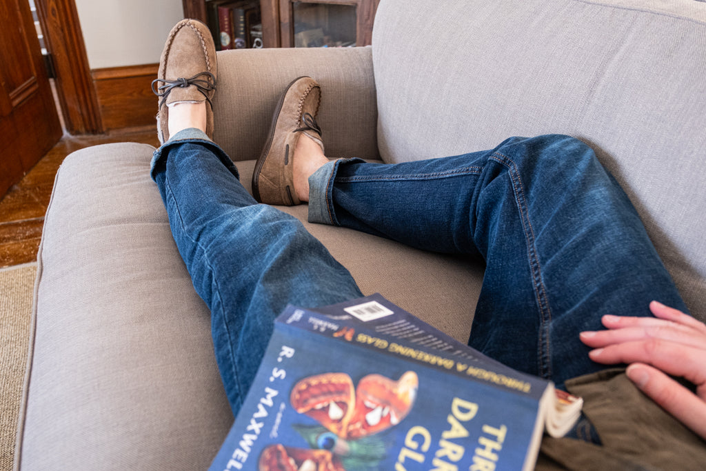 Lying on a couch reading a book wearing moccasins