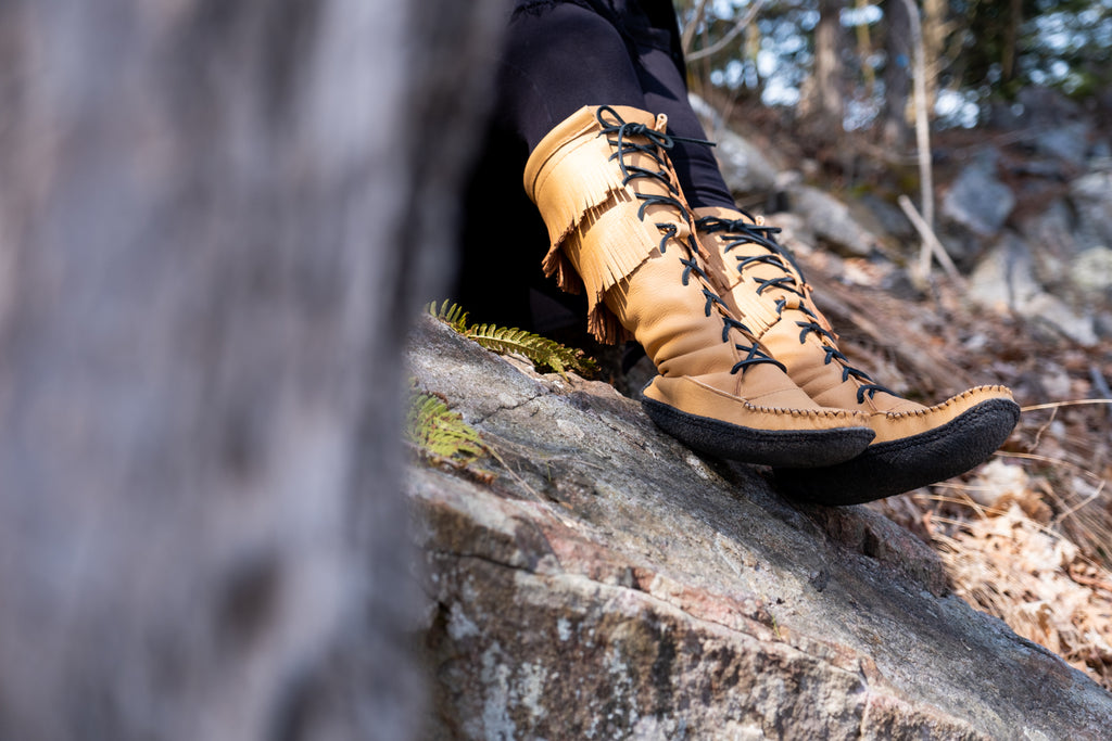 Wearing authentic knee-high moccasin boots hiking in the woods