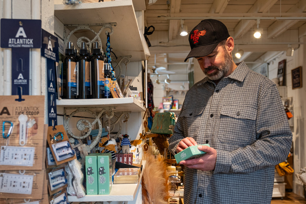 Guy browsing a store boutique wearing a black cap with indigenous native american art