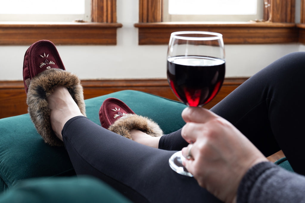 Enjoying a glass of red wine with a pair of burgundy colored moccasin slippers