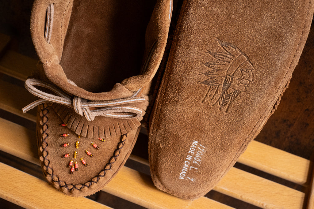 Suede sole moccasins slippers in a rich chocolate-brown color with a fold over fringe and beaded vamp.