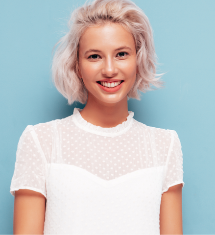 Mujer sonriente con blusa blanca y cabello de tono pastel 