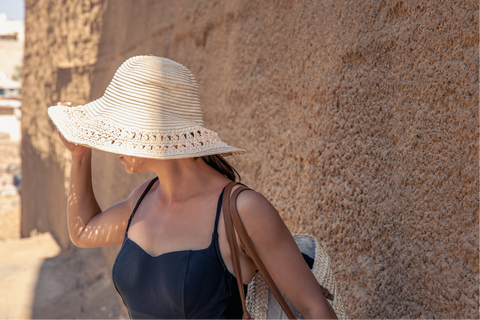 Mujer cubriendo su cabeza del sol con un sombrero