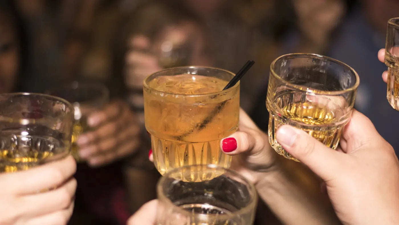glass of alcohol being held up by woman with red nails