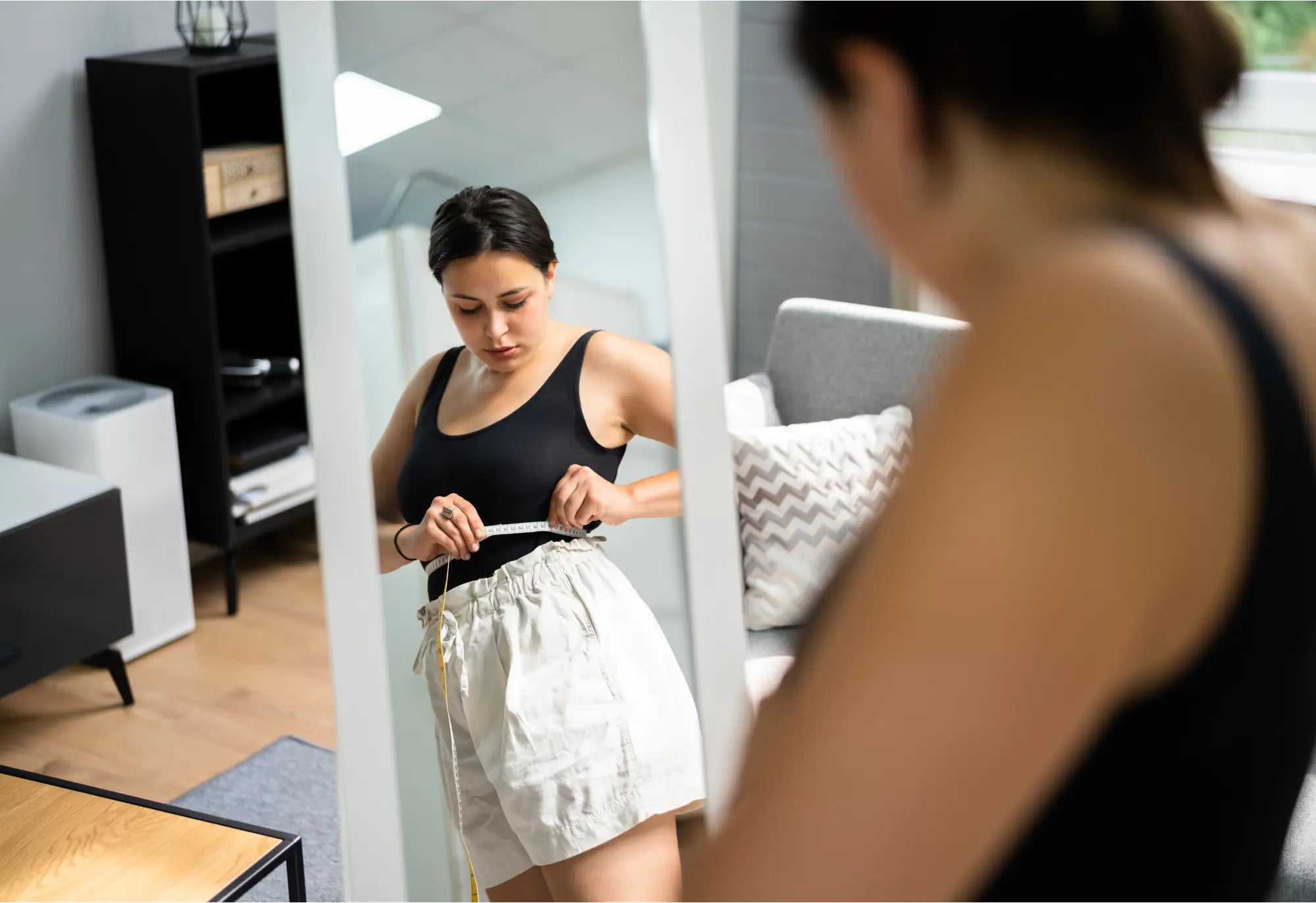 mujer morena comprobando la medida de la cintura en el espejo