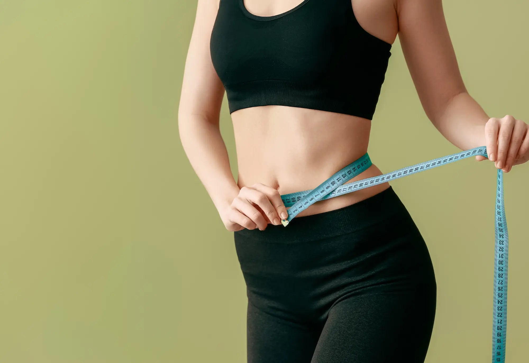 mujer con conjunto de gimnasia negro midiéndose la cintura