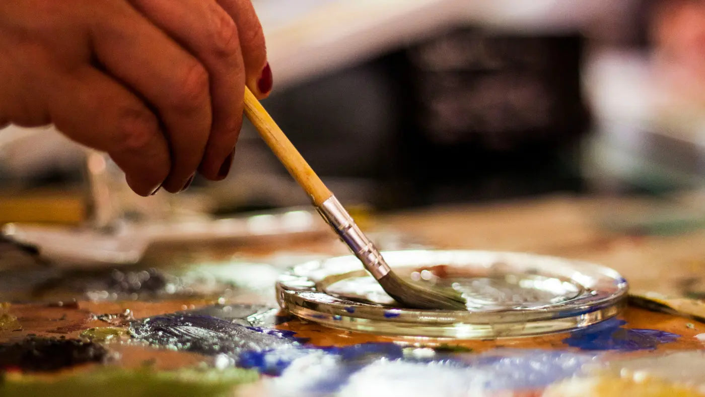 hand with paintbrush painting dish
